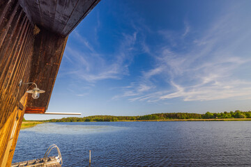 Beautiful nature landscape where serene summer lake merges into a vivid sky with delicate white...
