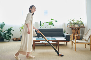 リビングで掃除機をかける20代女性