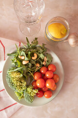 Harvested arugula, broccoli, cherry tomatoes and cashew on a plate in a kitchen marble table. Food ingredients concept