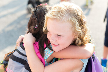 First day of school for young girl that is hugging her friend.