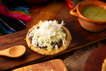 Sope. Traditional homemade Mexican food prepared with flattened and pinched on the border fried corn dough covered with refried beans, green or red sauce, lettuce, cheese, onion and sour cream. - 763626894