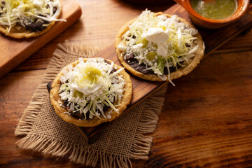 Sope. Traditional homemade Mexican food prepared with flattened and pinched on the border fried corn dough covered with refried beans, green or red sauce, lettuce, cheese, onion and sour cream. - 763627013