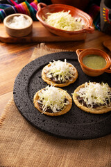 Sope. Traditional homemade Mexican food prepared with flattened and pinched on the border fried corn dough covered with refried beans, green or red sauce, lettuce, cheese, onion and sour cream.