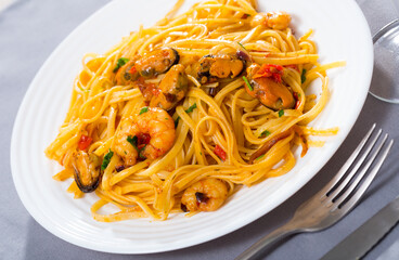 Image of delicious pasta of shrimps, mussels and greens at plate