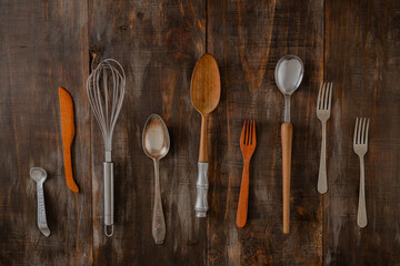 flat lay of different vintage cutlery items on dark wooden rustic board table
