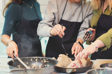 Group of people in a cooking class studio, adults preparing different dishes in the kitchen...