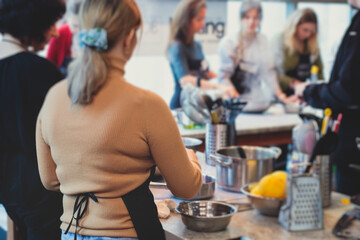 Group of people in a cooking class studio, adults preparing different dishes in the kitchen together, people in aprons learn on culinary master class, chef uniform, hands in gloves, italian cuisine