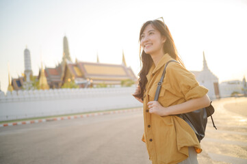 Traveler asian woman in her 30s, backpack slung over her shoulder, explores the intricate details...