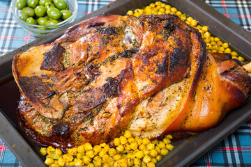 Roast whole pork knuckle served with chickpea on metal baking tray
