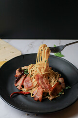 Spaghetti on fork with Dried Chili and Bacon on white table. Traditional Popular menu classic italian cuisine dish. Delicious spicy food.