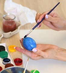 Woman paints Easter eggs with a brush and paints