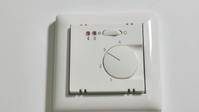 Warm floors switch.Heated floor control button. Control of the heating system in the house. Heating the house with warm floors.Hand turns on the floor heating. Heating control in the house. 