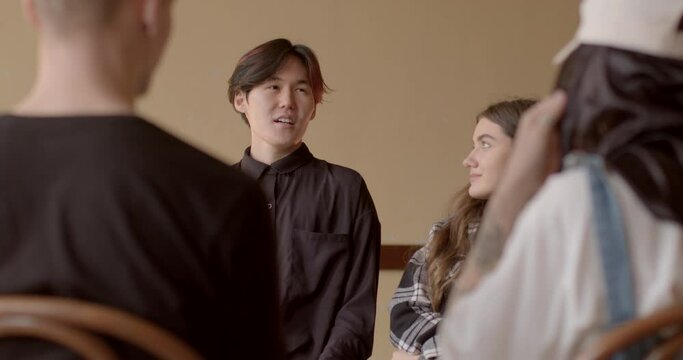 Person in club to improve public speaking, presentation. Debate Clubs background. Asian Man practice presenting arguments, open to feedback. Communication development and speech improvement of people.
