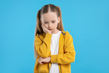 Portrait of sad girl on light blue background