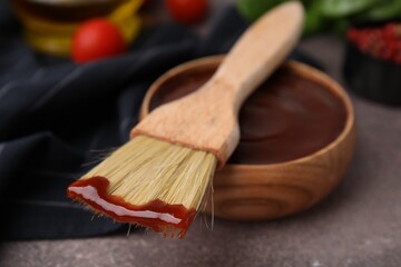 Marinade in bowl and basting brush on brown table, selective focus