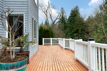 Freshly stain large home walk out cedar wood deck patio during early spring