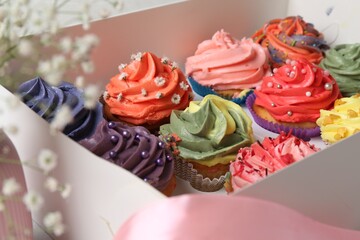 Different colorful cupcakes in box, closeup view