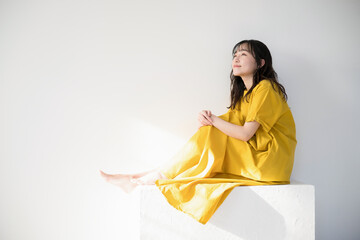 日差しを浴びて黄色のドレスを着た女性　美容やビューティー　太陽のイメージ　日焼けやUVなど