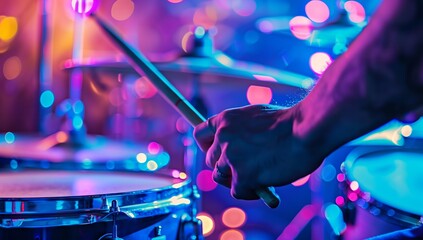 A musician playing drums, a type of membranophone, in a dark room with purple and blue lighting....