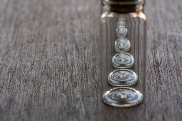 hilera de frascos de vidrio enfocando en la base circular, sobre mesa de madera con espacio para...