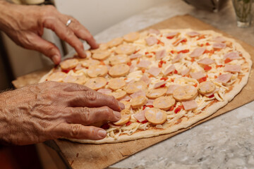 Veteran man making pizza at home for his family. Man cooking with love. Professional cook baking pizza. Lifestyle.