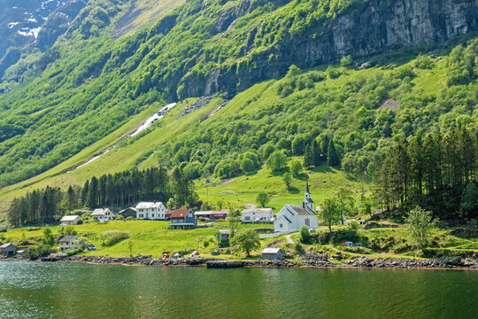 Quaint village of Bakka nestled along the coast of the fjord mountains and forest in Aurland from an angle