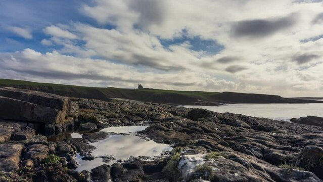 Timelapse of rugged rocky coastline on sunny cloudy day with Classiebawn castle in distance in Mullaghmore Head in county Sligo on the Wild Atlantic Way in Ireland.