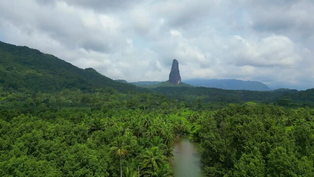 Flying over the caué river surrounded by the green forest towards the peak Cão Grande an elevation of volcanic origin. Rises over 300 m above the ground at São Tomé,Africa.