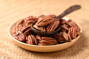 Raw peeled pecan nuts in wooden plate with spoon, Food ingredient