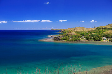 Fototapeta na wymiar The village of Umatac, along Guam's western coastline, with blue skies and turquoise water 