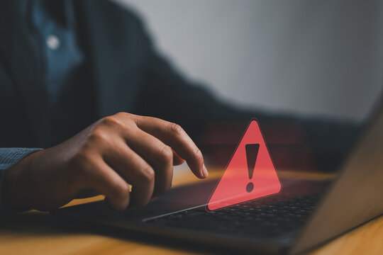 Businessman or it staffs, programmer, developer using computer laptop with triangle caution warning sign for notification error and maintenance concept. Hack system alert, warning computer system
