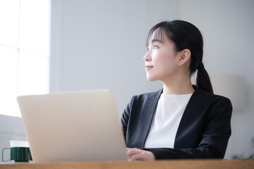 パソコンを使う女性　窓の方を見上げるクローズアップ