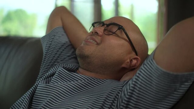 Relax moment of asian man lying on comfortable sofa in living room. Cozy couch breath fresh air inside living room. Male fall asleep take a nap ventilated condition air in Leisure time.