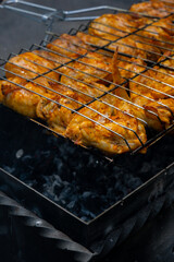 Delicious chicken frying on barbecue grill grate outdoor. Seasoning falling on fresh grilled chicken wings. Summer party food ideas. BBQ Juicy roasting chicken grill legs