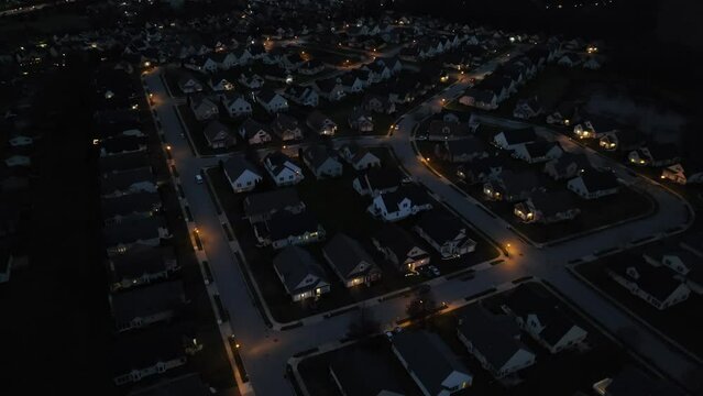 High aerial shot of dark neighborhood at night. Development with house and street lights in USA housing area.