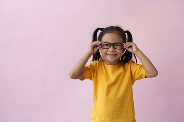Portrait of a stylish little girl with fingers pointing up Little boy wearing glasses has an idea creative concept Child on pink background with copy space success bright ideas.