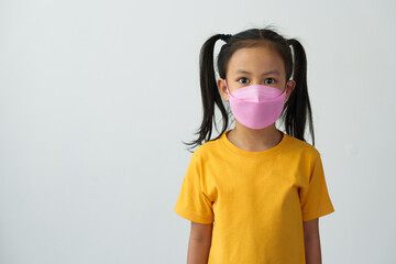 Little Asian girl wears a mask to help her breathe and protect her from dust, smoke, PM2.5, virus outbreaks, germs, and disease prevention concepts for the lungs, respiratory tract, and brain..