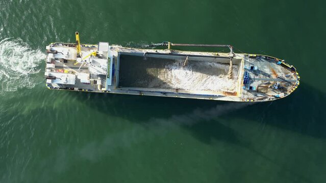 Sand dredging vessel positioned in a city shipping channel to remove built up sand from the waterway. Drone view