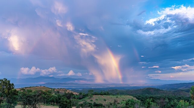Amidst the chaos and fury of the monsoon rains a majestic rainbow stretches across the sky offering a brief moment of respite in the midst of the storm.