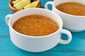 メキシコの牛肉のバルバコアのコンソメ 　ライムを添えて 青背景　コピースペースあり
Mexican consomé de barbacoa de res (consommé of beef barbacoa) with lime on blue background, copy space available
