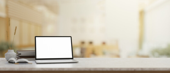 A white marble table features a laptop mockup with a blurred background of a modern meeting room.