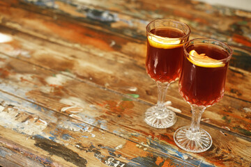 Crystal Glasses with Cold Drink on Weathered Table. Crystal stemware holding a cold dark drink and orange garnishes, on a weathered wooden table backdrop