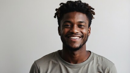 Portrait of young happy black african american man smiling standing in front of blank white wall looks in camera