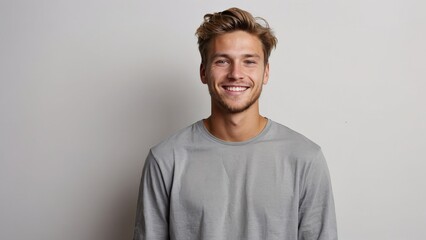 Portrait of young happy white caucasian man smiling standing in front of blank white wall looks in camera