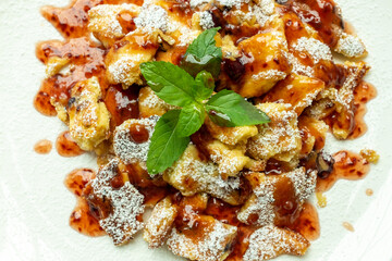 Kaiserschmarrn with iceing sugar and apple sauce on a white plate