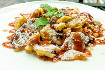 Kaiserschmarrn with iceing sugar and apple sauce on a white plate