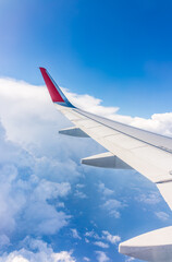 Fototapeta premium View from the airplane window at a beautiful cloudy sky and the airplane wing