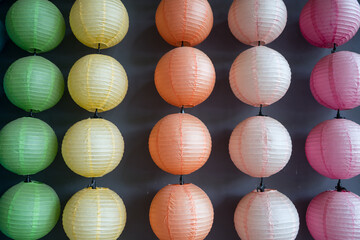 Hanging colorful Japanese lantern on row with dark background. Handcrafted lampshades.