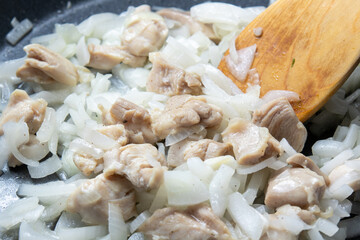 鶏もも肉と玉ねぎをフライパンで炒める調理シーン。
