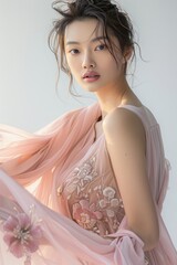 Portrait of a pretty young woman super model of Chinese ethnicity draped in an ethereal pink chiffon gown with a sweetheart neckline, delicate floral 